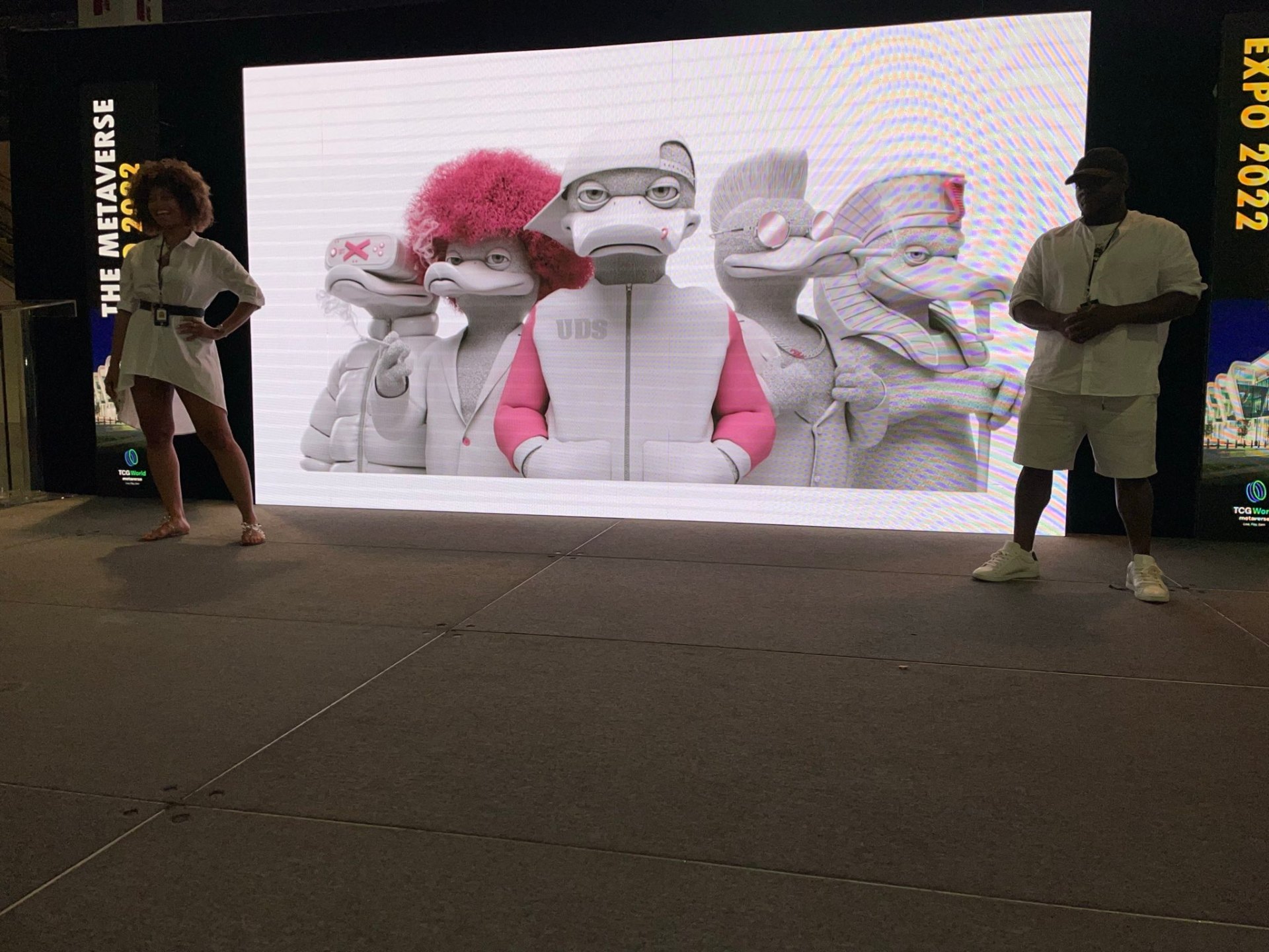 Scrooge and Mother Duck presenting the Ducks on stage at a metaverse expo